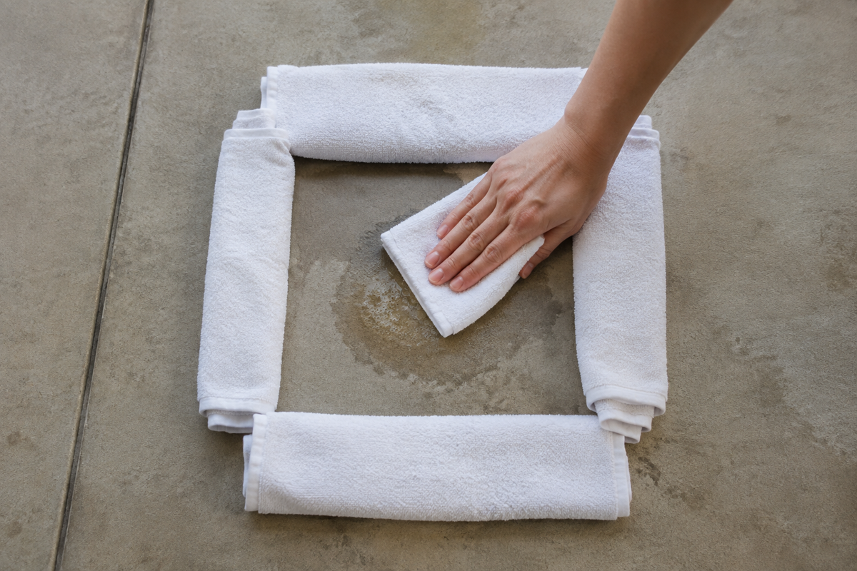 Containing and blotting a small dog urine accident on concrete without spreading runoff.